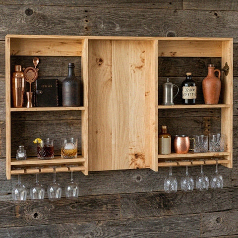Large rustic wooden wall-mounted bar shelving unit with light wood, open compartments, door panel, and glassware racks for garden bar setup