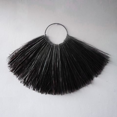 Black bristle brush with circular metal handle featured with large seagrass fan wall decor in black color