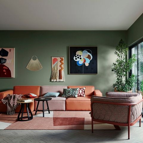 Orange sectional sofa with cushions and checkered throw in front of large natural seagrass fan wall decor for wall decor