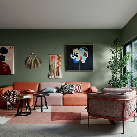 Large seagrass fan wall decor with zebra pattern shown above an orange leather sofa with patterned cushions and checkered throw