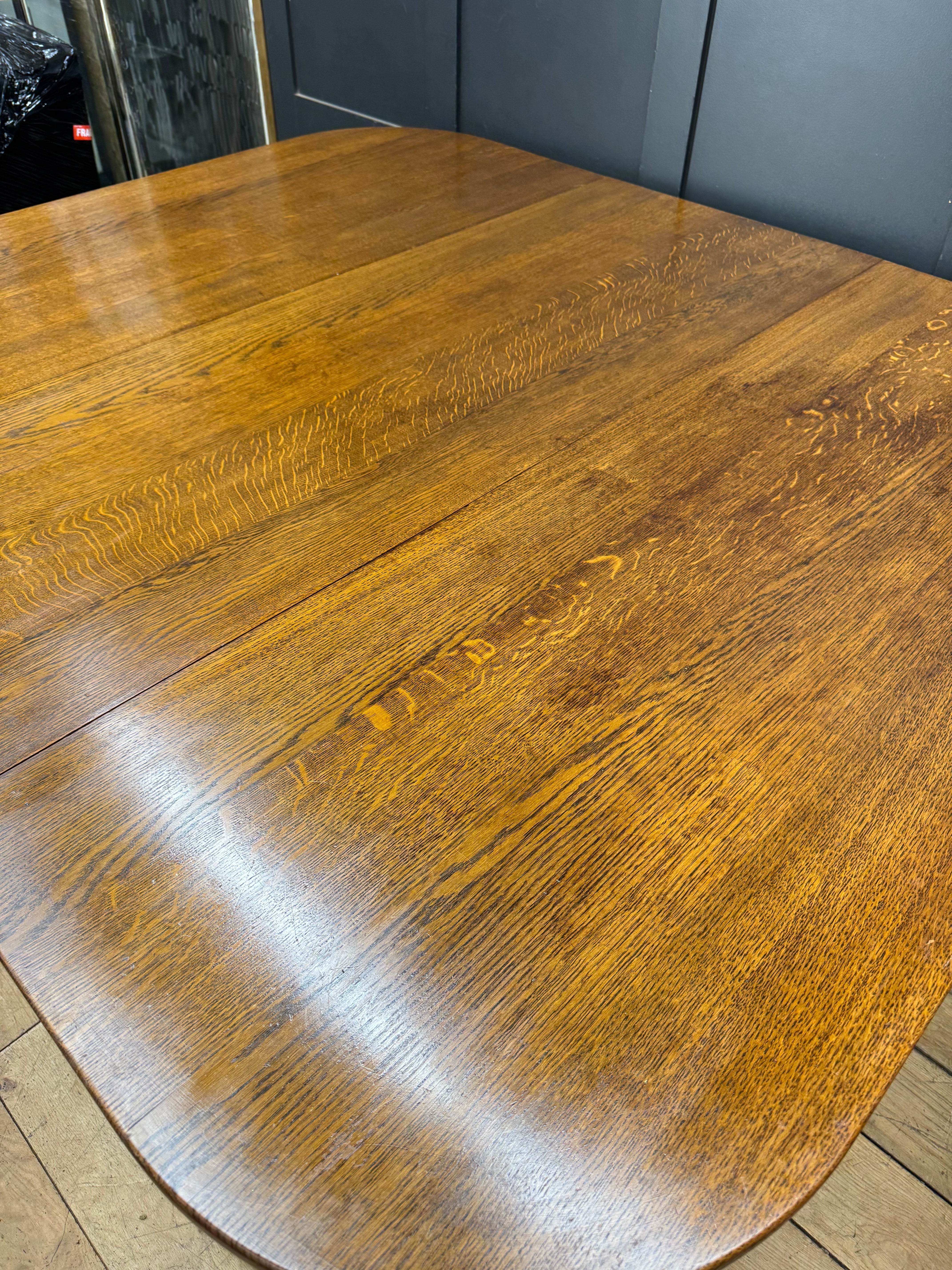 Large solid oak gateleg dining table in rich amber finish with smooth polished surface and visible wood grain