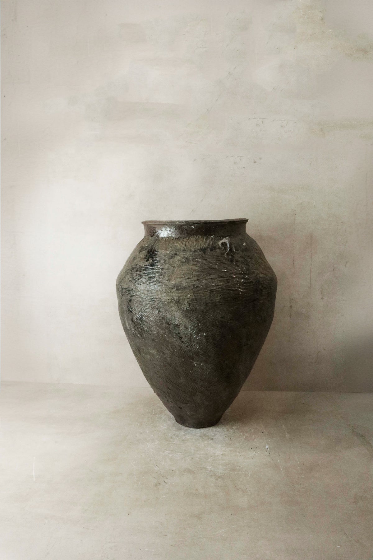 A large vintage brown glazed ceramic pot with a dark textured surface wide mouth and tapered body