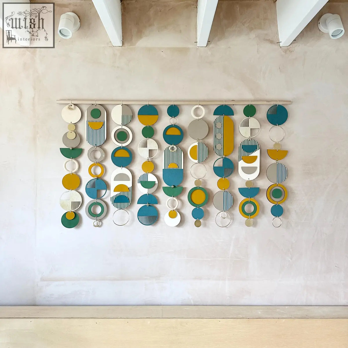Large wall art featuring geometric wood design with teal, mustard yellow, white, gray, and green shapes over the bed decor