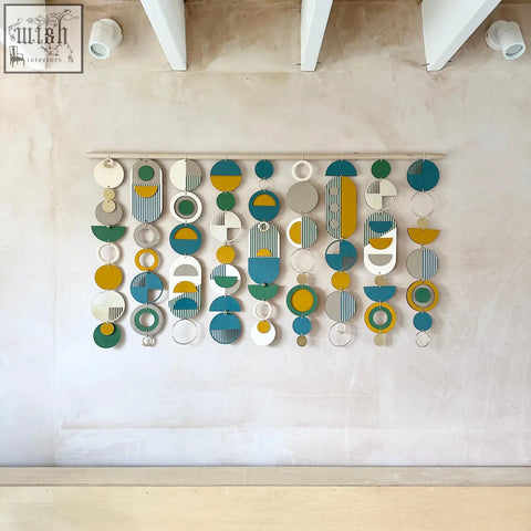 Large wall art featuring geometric wood design with teal, mustard yellow, white, gray, and green shapes over the bed decor