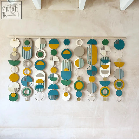 Large wall art wood piece with geometric layered circles in teal mustard yellow white gray and green for over the bed decor