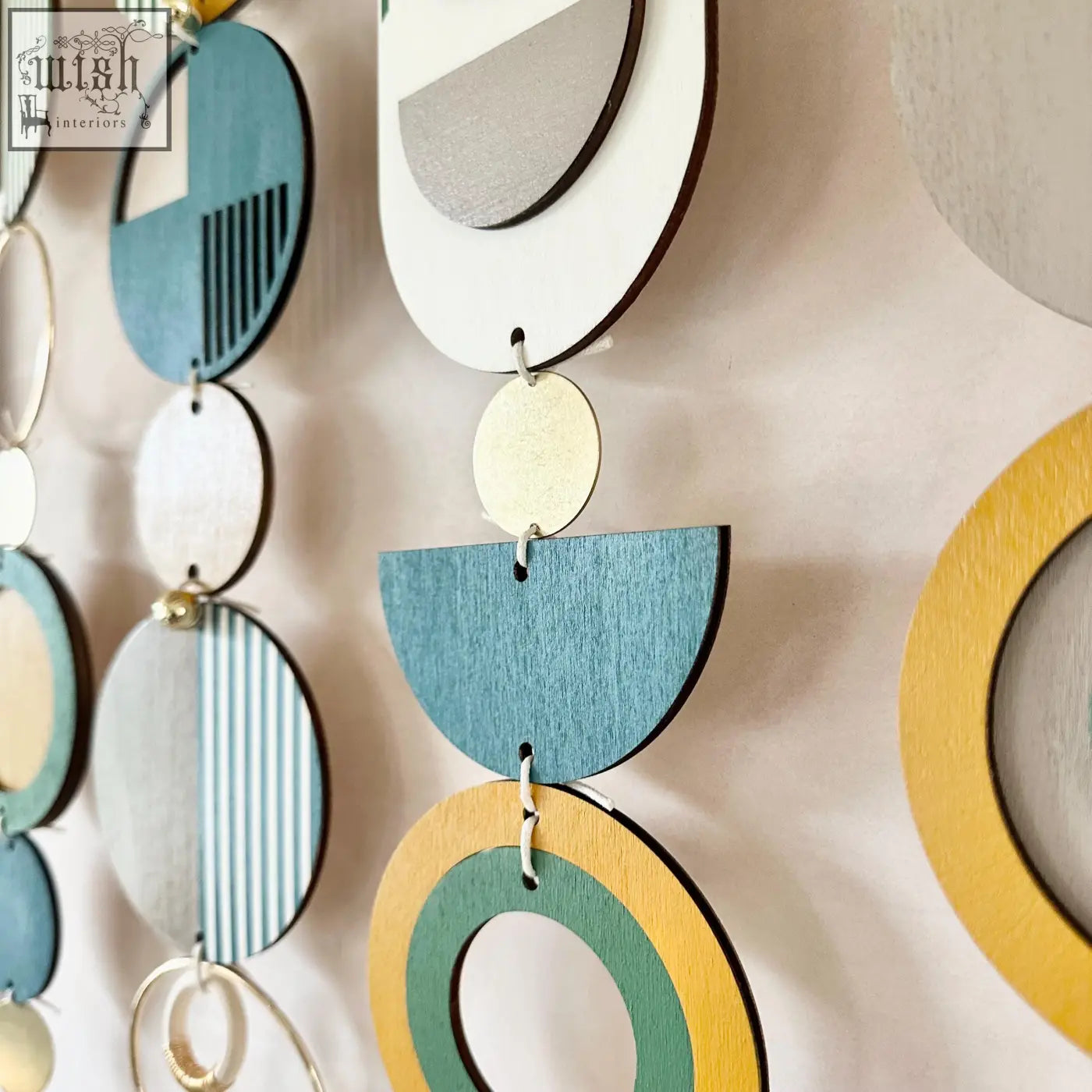 Large wall art featuring layered teal white yellow and gray wooden discs with geometric patterns for over the bed decor