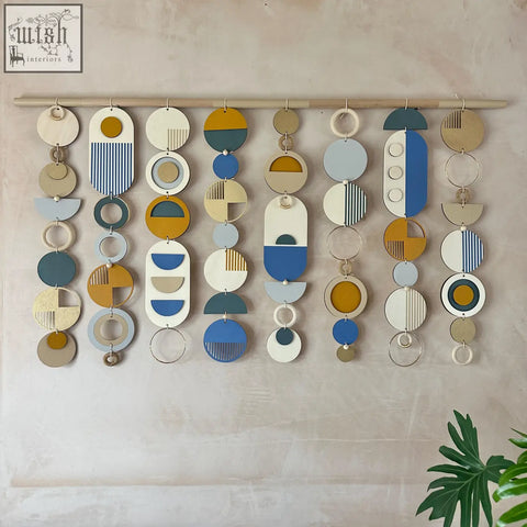Large wood wall hanging with layered circular shapes in muted blues yellows whites and beiges for modern wall decor