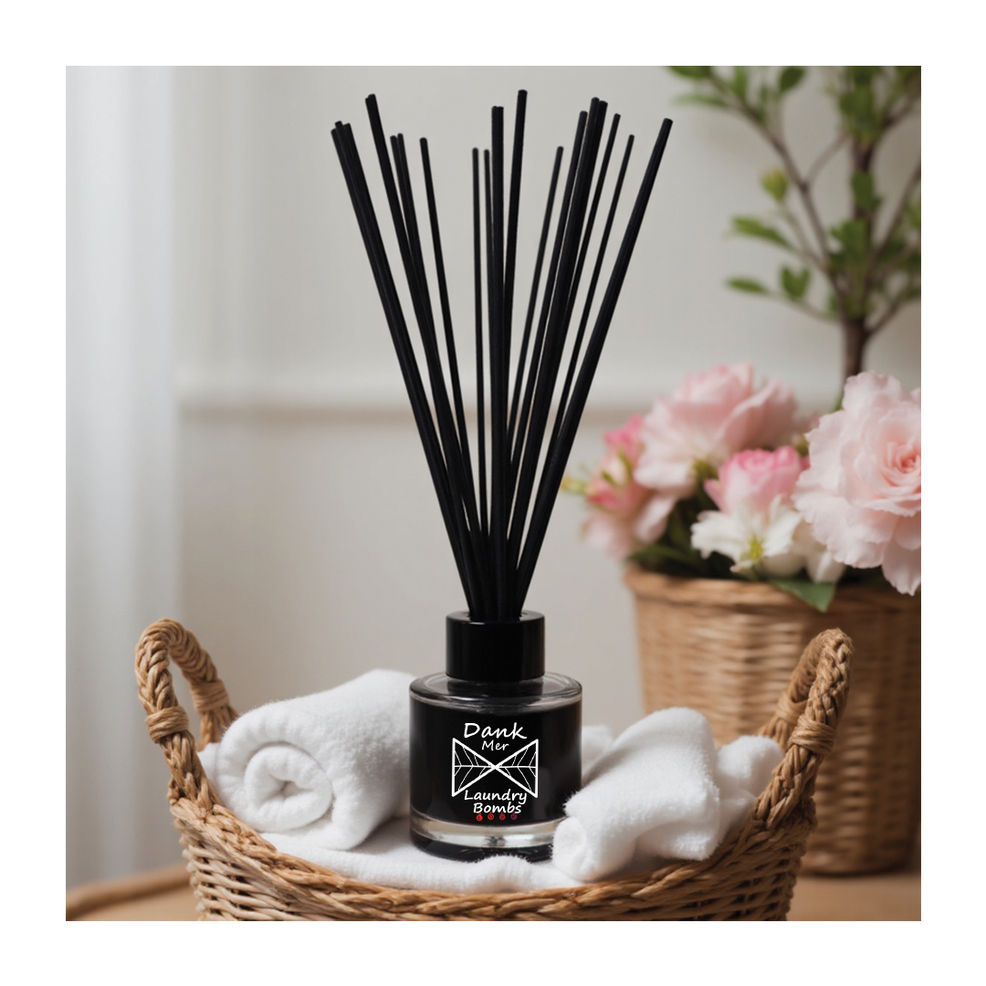 Black reed diffuser with fragrance oil in sleek glass bottle and minimalist logo nestled in woven basket with white towels
