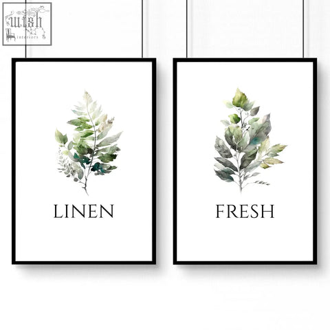 Two framed laundry room art prints with watercolor leaf illustrations in soft greens and grays labeled linen and fresh