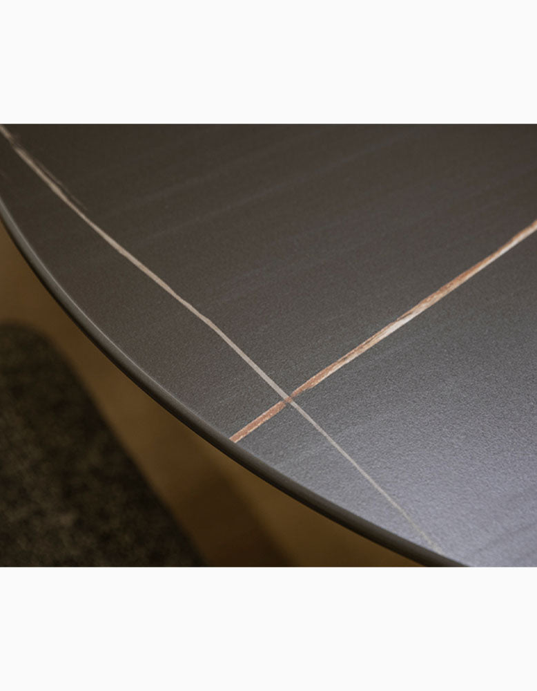 Dark gray sintered stone lauren dining table with subtle light and warm copper veining on marble tabletop
