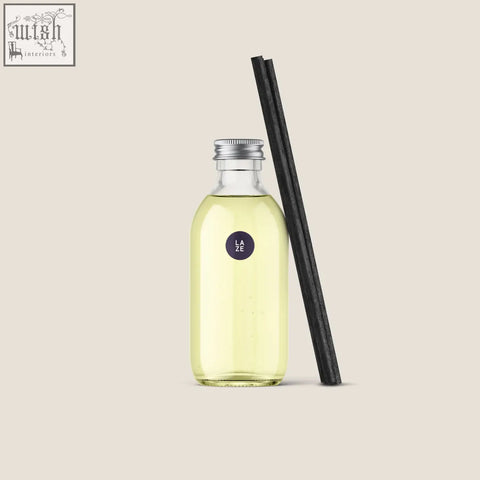 A clear glass bottle with pale yellow diffuser refill and black reed sticks labeled laze 200ml diffuser refill