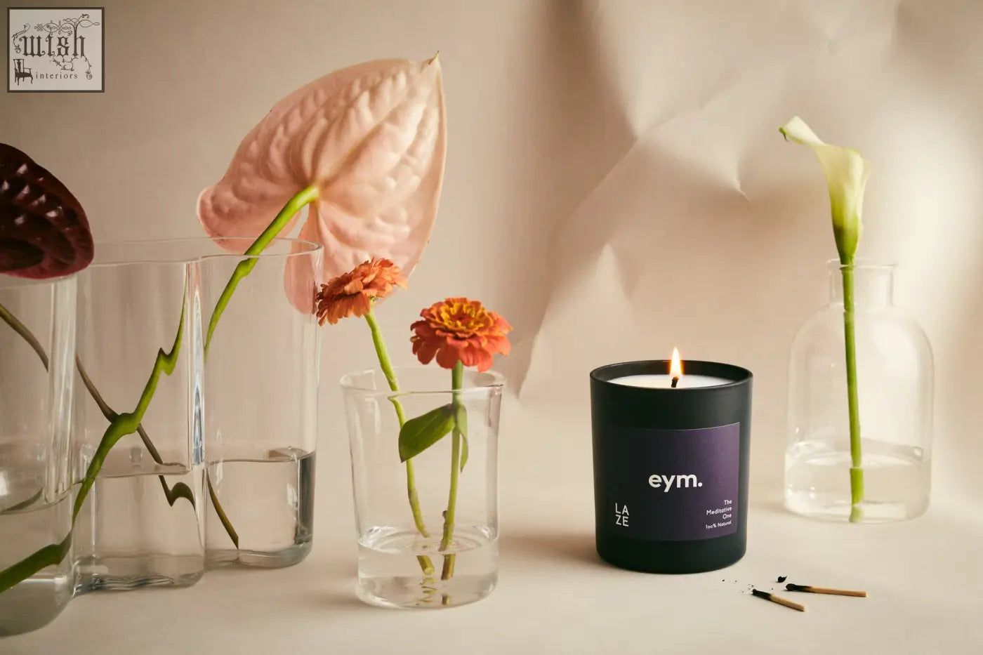 Black cylindrical standard candle with lit wick and purple eym label named laze for cozy ambiance