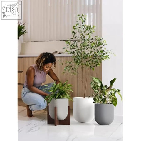 White ceramic plant pot with drainage hole on dark wood stand perfect for indoor plants and home garden use