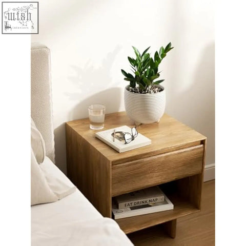 Light wood grain nightstand with single drawer and open shelf holding white ceramic plant pots for indoor use