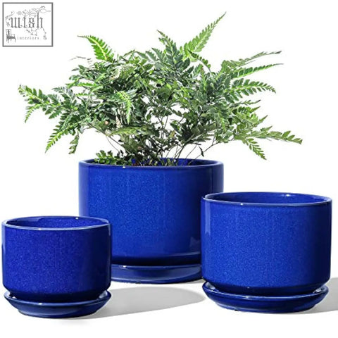 Set of three sapphire blue ceramic planters with drainage holes and matching saucers featuring speckled glaze finish