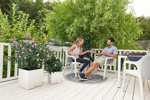 White woven resin patio chairs next to lechuza self watering plant pots cube cottage 40 rattan look planter