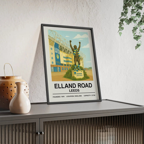A framed vintage-style print of elland road leeds stadium with a bronze statue wearing a blue and white scarf in front