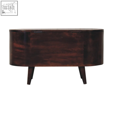 Dark brown wooden oval side table with tapered legs next to light walnut rounded lid-up blanket box storage bench