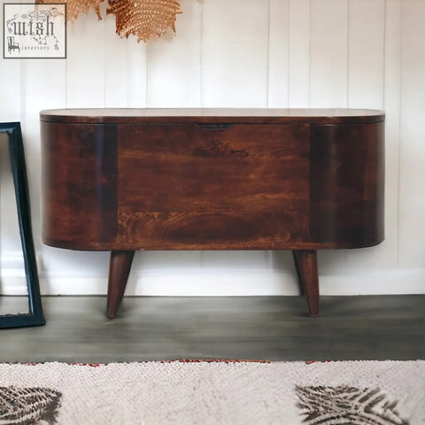 Dark brown wooden sideboard with curved top and tapered legs next to a light walnut rounded lid-up blanket box storage bench