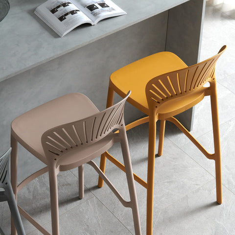 Modern lilith bar stools with sleek molded plastic sunburst seats in matte beige and mustard yellow colors