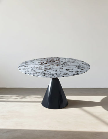 A lillian round dining table with a sleek white and black marble top and a glossy black conical base perfect for dining