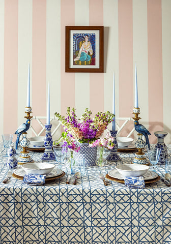 A vibrant bouquet of purple and pink flowers in a blue and white ceramic vase on lily’s blue bamboo breeze tablecloth