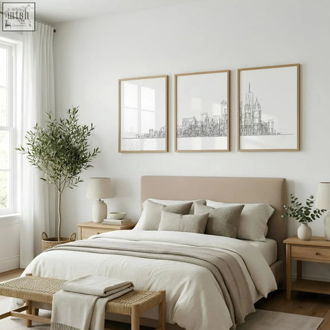 Beige upholstered bed with matching pillows and neutral duvet below city skyline line art wall art prints set of 3