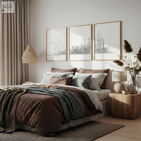 Cozy bed with earthy linens and knit throws beneath line art city skyline skyscraper wall art prints set of 3