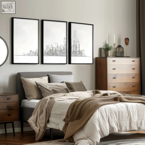 Gray upholstered bed with multiple pillows and beige throw blanket beneath city skyline line art wall art prints set of 3