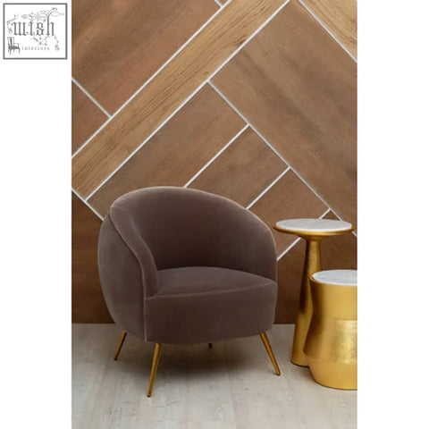 A plush taupe velvet armchair with slender gold legs paired with a lino large gold side table in a stylish setting