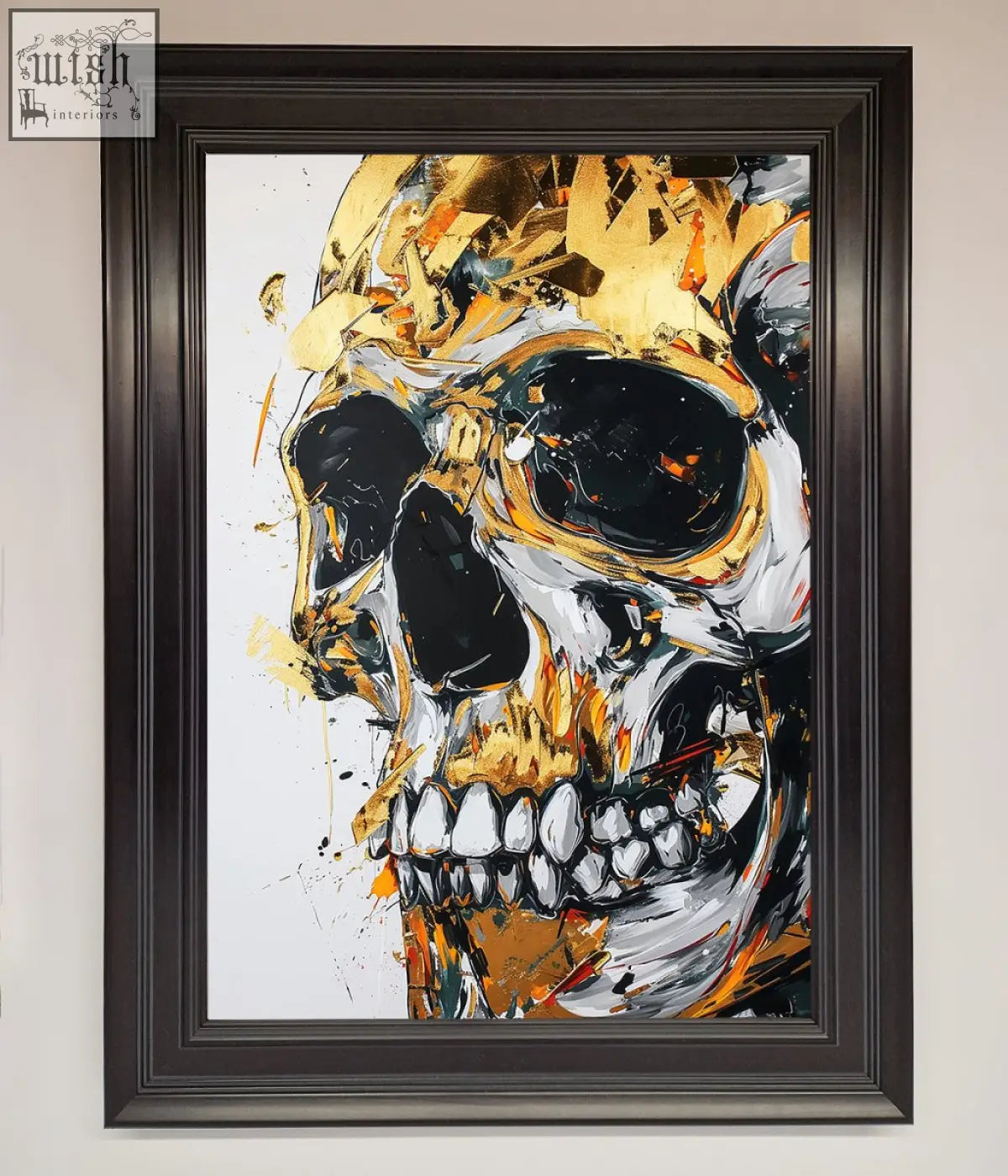 A liquid gold skull framed print with bold gold splatters black accents in a dark brown frame on white background