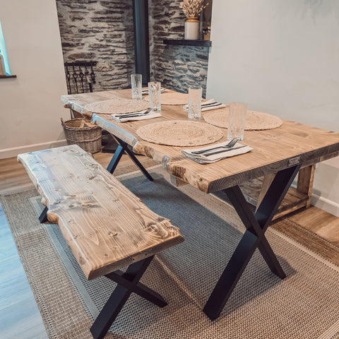 Rustic waney edge dining table with live edge wooden top and black x cross metal legs perfect for edge dining