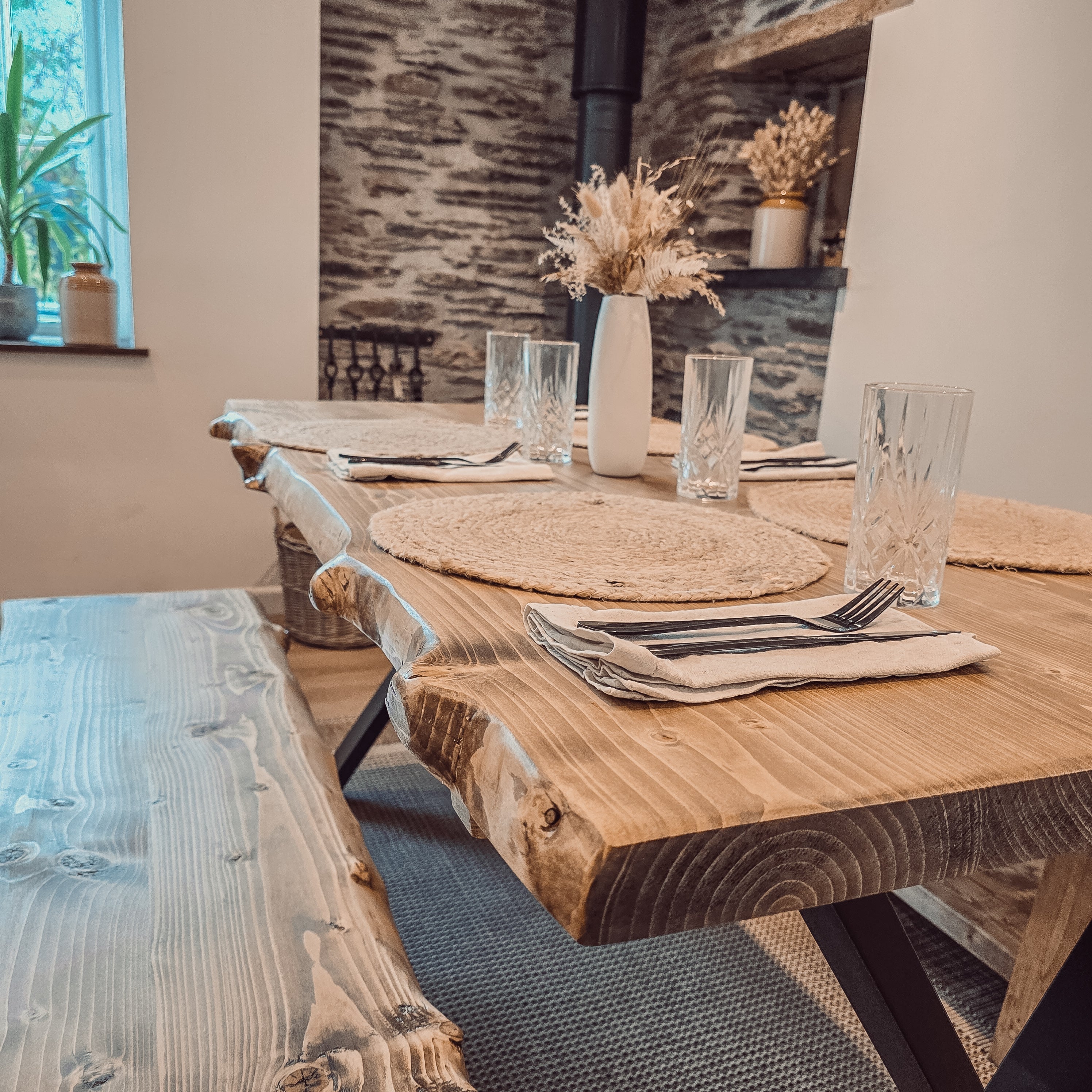 Rustic wooden waney edge dining table with black x cross metal legs perfect for a cozy dining space