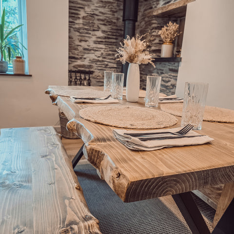 Rustic wooden waney edge dining table with black x cross metal legs perfect for a cozy dining space