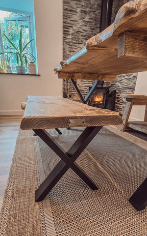 Rustic waney edge dining table with natural wood grain top and black x cross metal legs perfect for dining rooms
