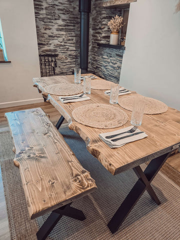 Rustic wooden waney edge dining table with live edge top and black x cross metal legs for edge dining table setup