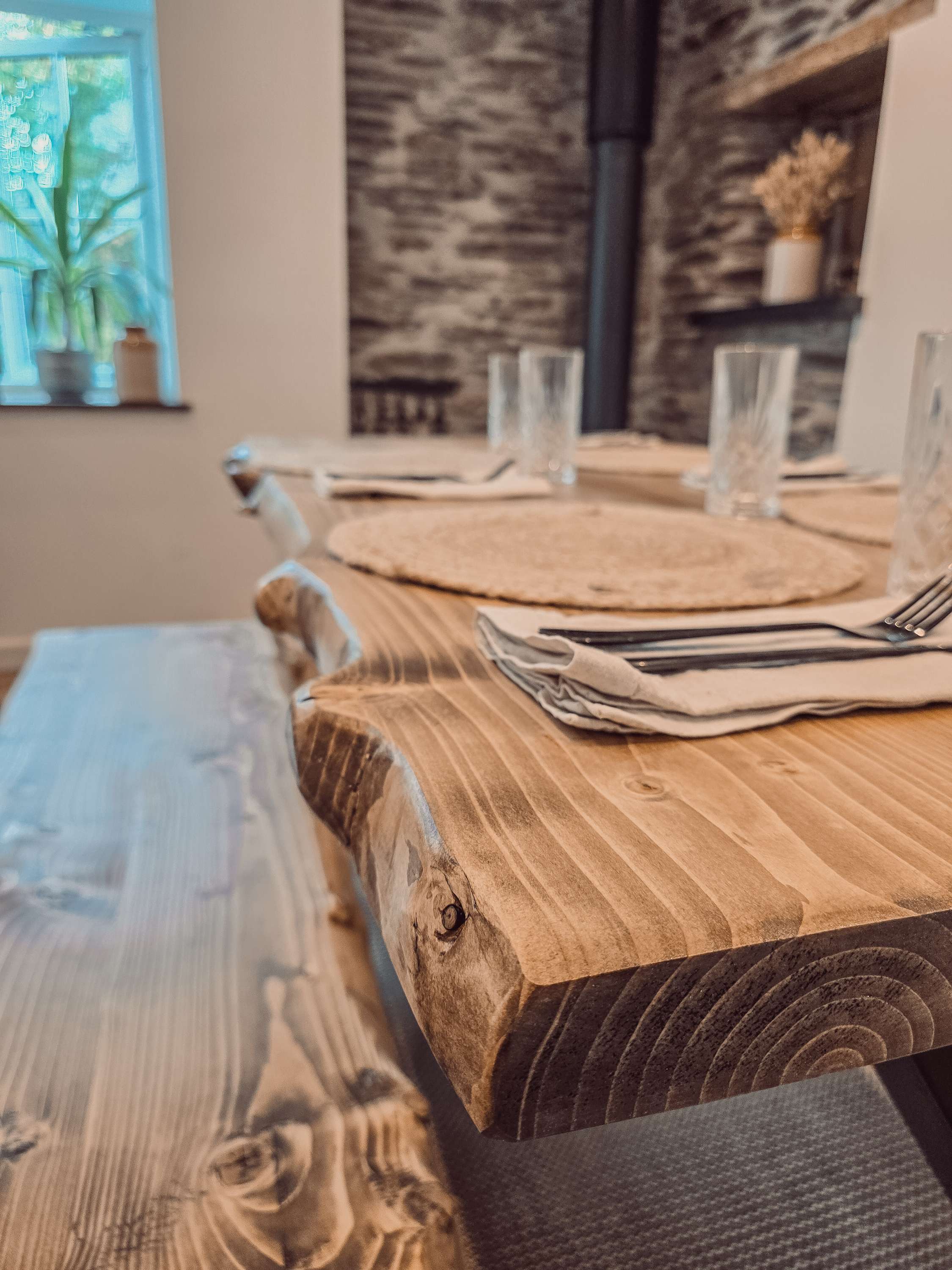 Rustic wooden live waney edge dining table with visible grain and x cross black metal legs for edge dining table setup