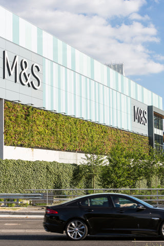 The m&s store facade features a living wall with interchangeable plant cassettes in green and white stripes