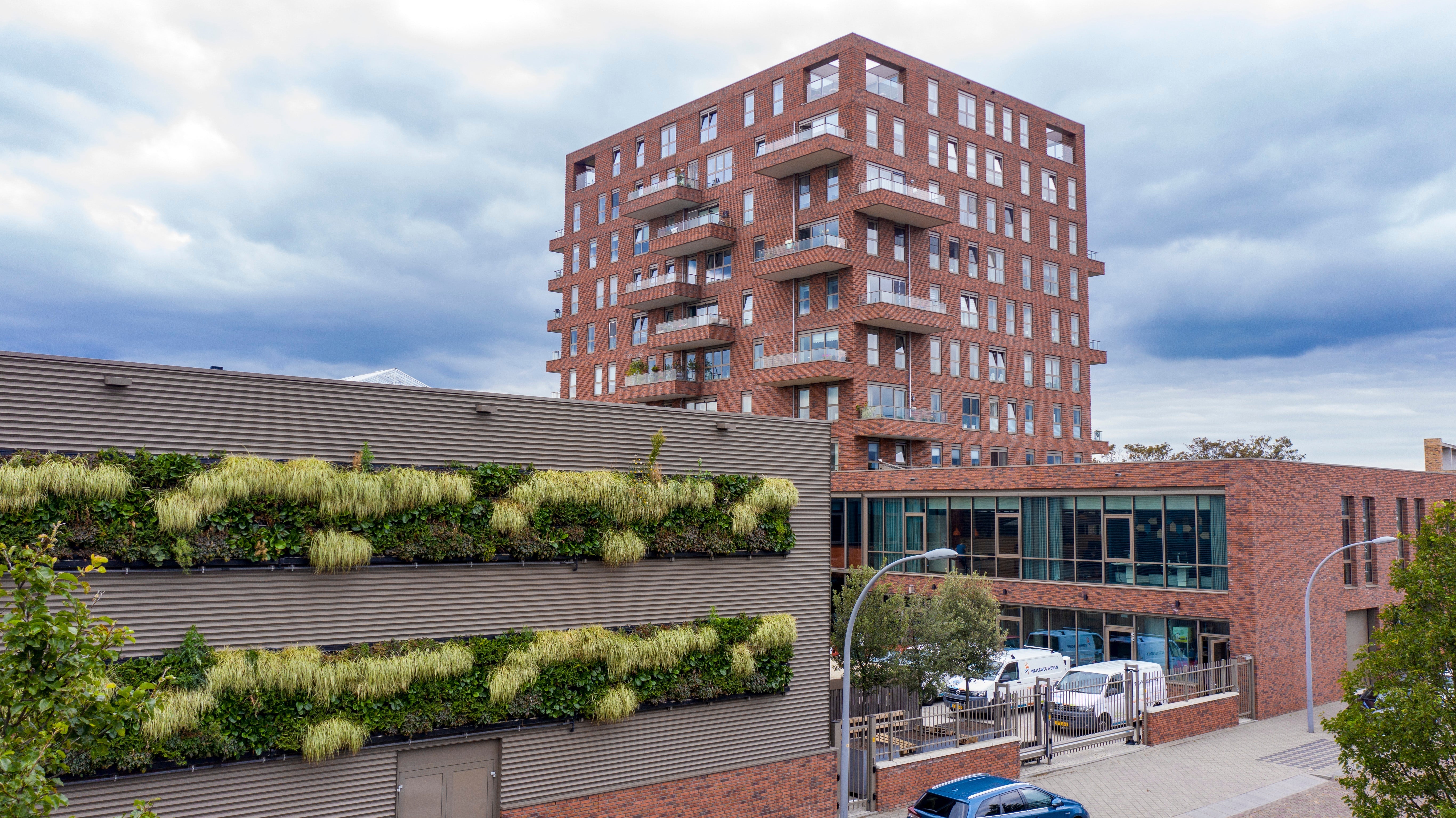 Red brick apartment with balconies featuring a living wall using interchangeable plant cassettes from livepanel outdoor living wall