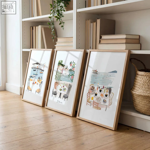 Three living room artwork pieces featuring mediterranean coastal dining scenes in soft watercolor and light wood frames