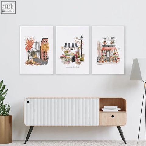 Set of three autumn new york cityscape watercolor prints with warm tones as living room wall art above wooden table