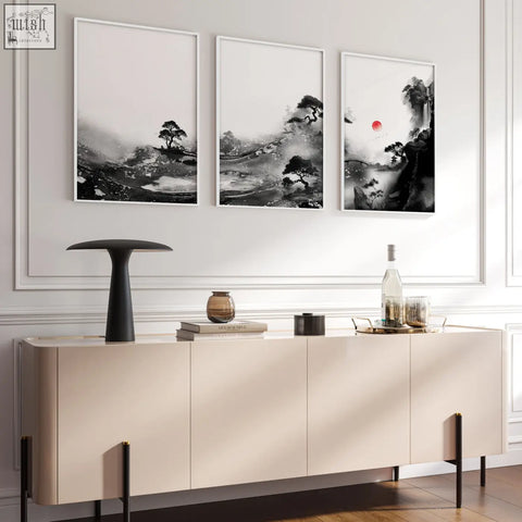 Three framed black and white japanese ink landscape wall art paintings with red sun above beige console for living room wall