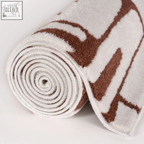 A plush white and brown geometric patterned loft abstract terra rug rolled to show its soft texture
