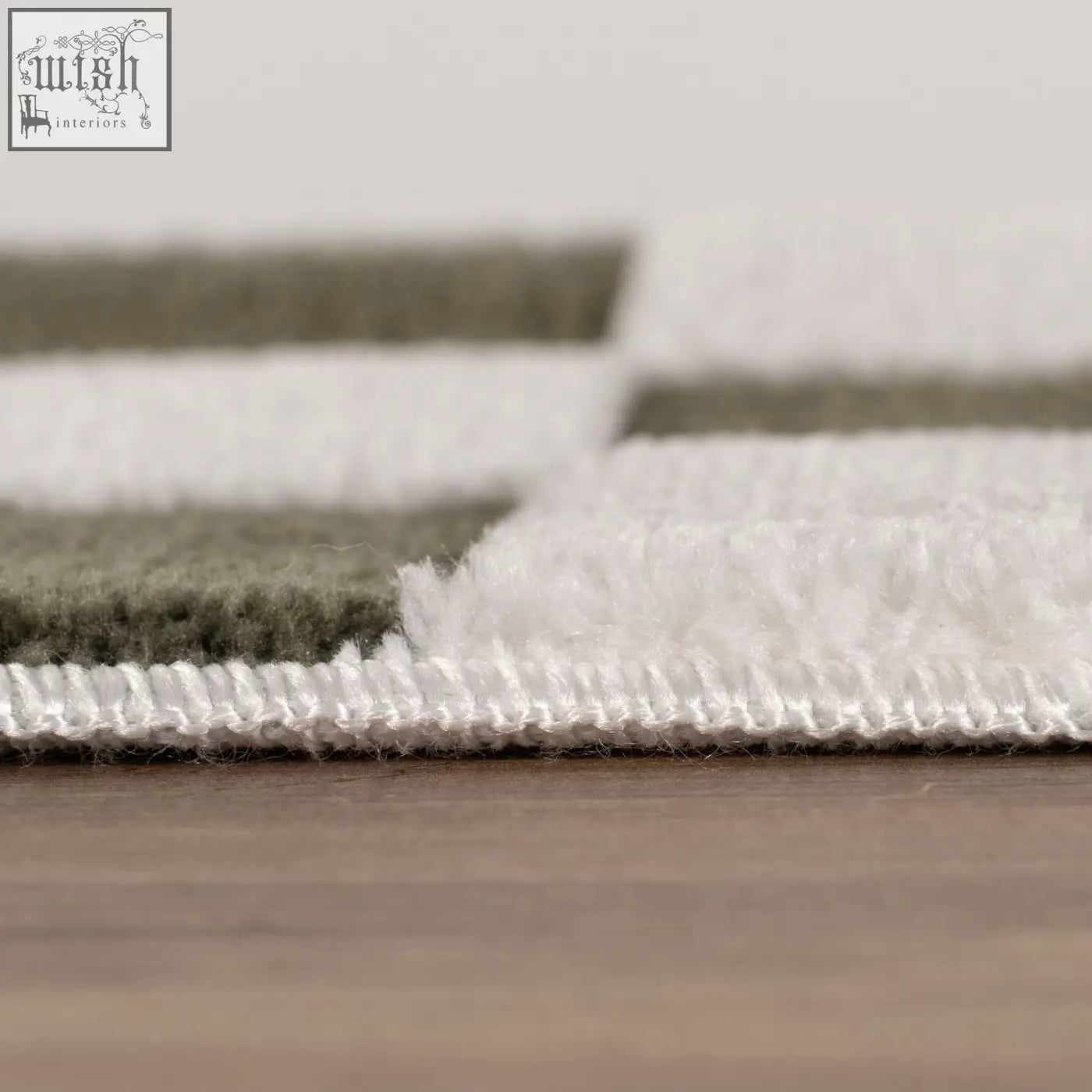 A plush green rug with a loft checkerboard pattern of white and olive green stripes and a stitched border