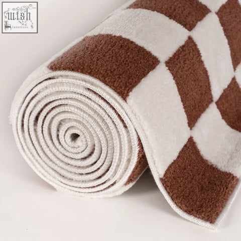 A plush rolled bath mat with a cozy brown and white diamond pattern from the loft checkerboard terra rug collection