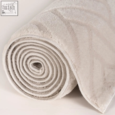 A plush light gray chevron cream rug with a soft textured surface and subtle woven pattern rolled up