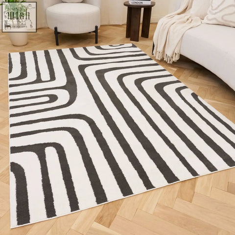 A modern dark grey rug with bold black and white geometric patterns and flowing lines perfect for loft spaces