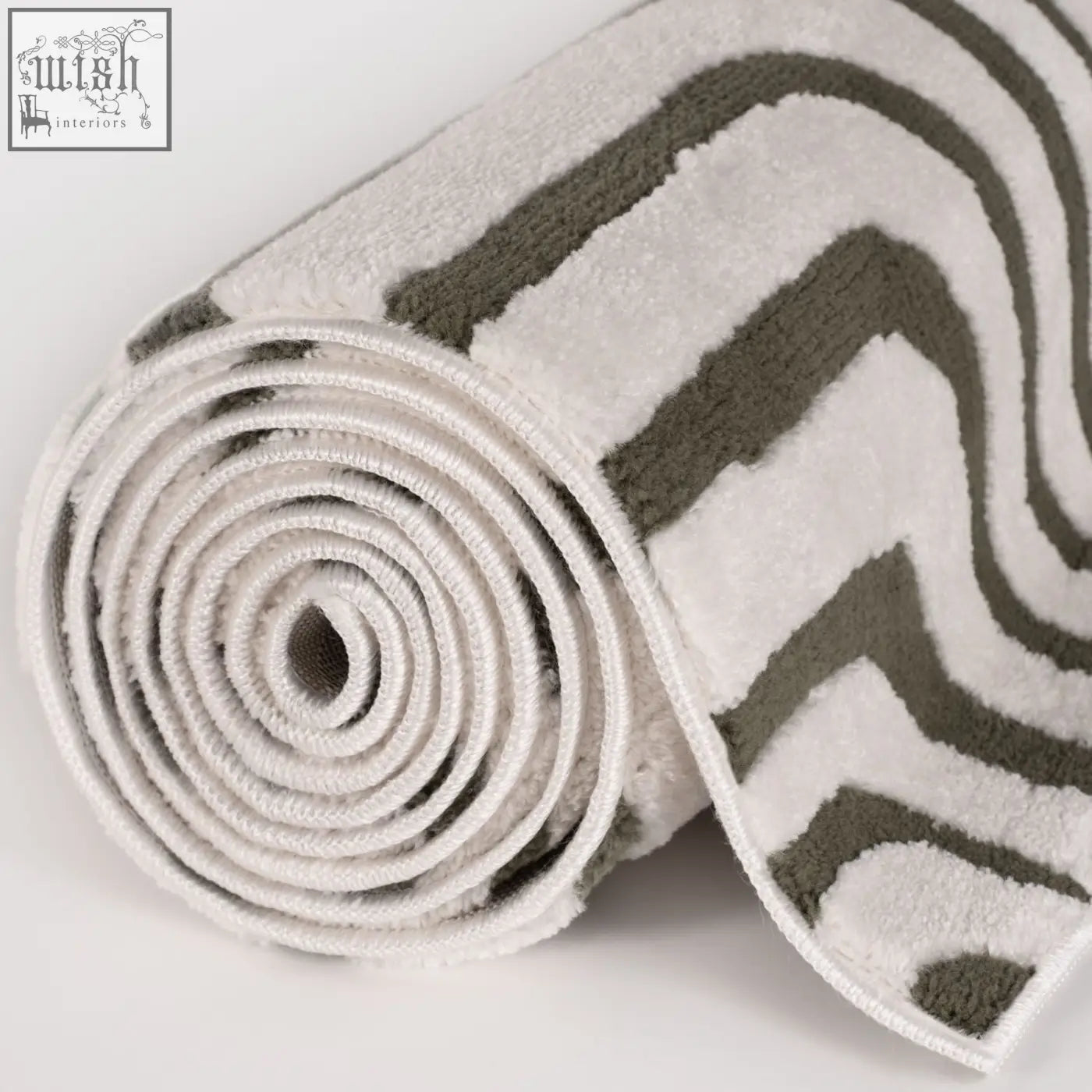 A plush rolled bath mat with a modern zigzag pattern in white and gray perfect for loft geometric green rug decor