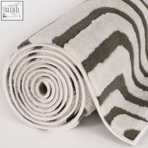 A plush rolled bath mat with a modern zigzag pattern in white and gray perfect for loft geometric green rug decor