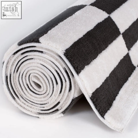 A plush dark grey rug with a soft textured surface featuring a black and white checkered pattern